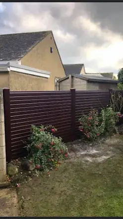Dark horizontal-board fence along a garden boundary with shrubs in front