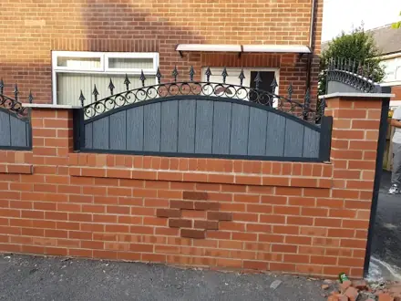 Grey infill panel with arched black railings above a red-brick boundary wall