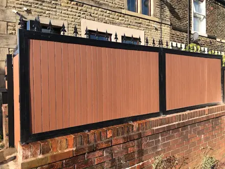 Wood-effect panels in a black frame with pointed finials above a brick wall