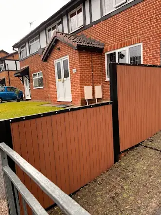 Wood-effect infill panels in a black metal frame beside a house